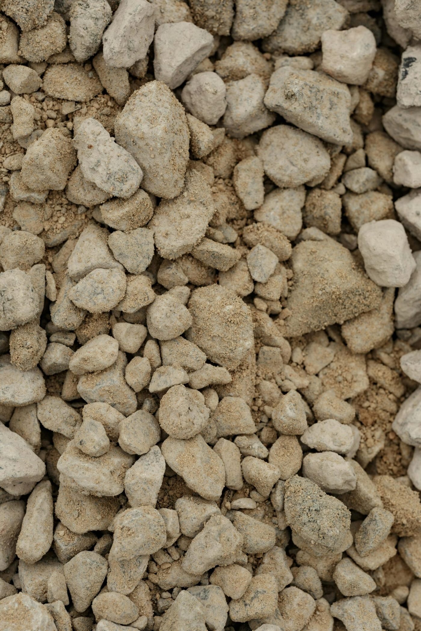 Detailed close-up image of rough textured pebbles and stones on a sandy ground.